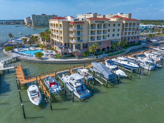 Panoramic view of a waterfront building with a marina and swimming pool.