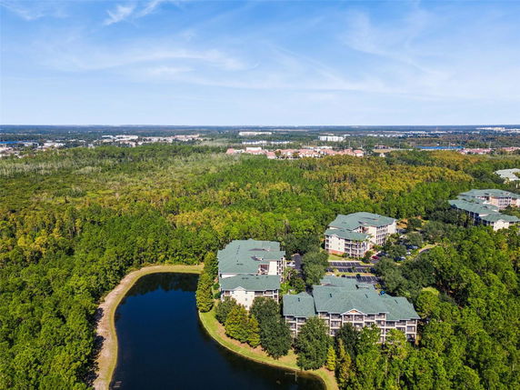 Aerial view of apartment complex surrounded by trees and a small lake.