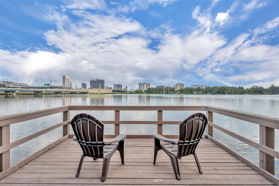 Panoramic view from a deck over a body of water with buildings in the distance.
