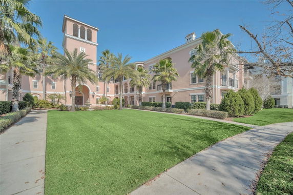 Front view of a large building with arches and palm trees.