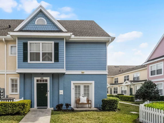 Front view of a two-story blue townhouse with white trim, green shutters, and a small porch.