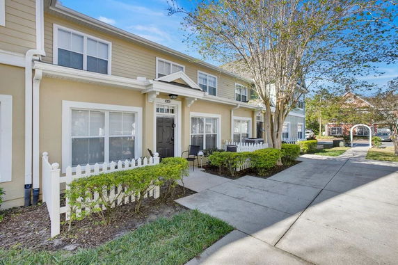 Front view of a two-story townhouse with a small front yard and white picket fence.