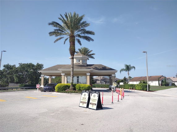 Front view of a building with a central tower and palm trees nearby.
