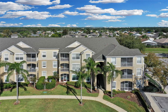 Front view of a multi-story apartment building with balconies and palm trees.