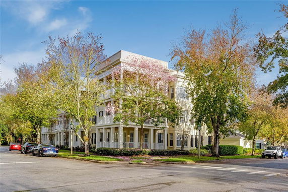 Front view of a multi-story building with balconies and surrounded by trees.