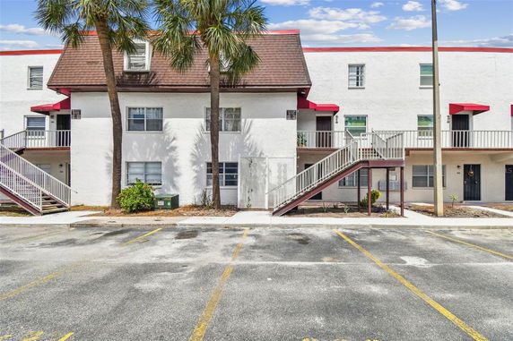 Front view of an apartment building with an exterior staircase and red awnings.