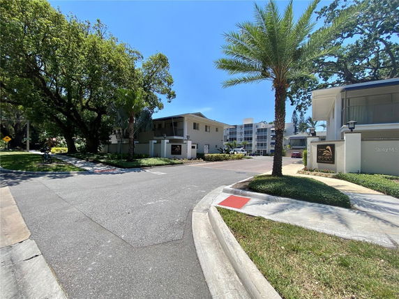 Front view of a residential building with palm trees and a driveway entrance.