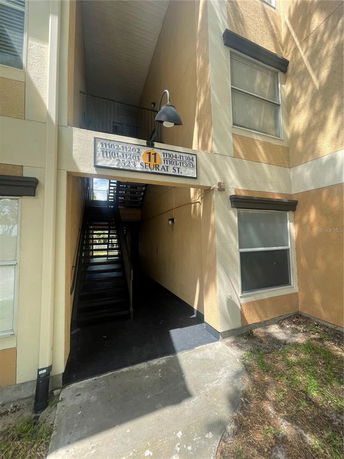Front view of a multi-story building with exterior stairs and a sign above.
