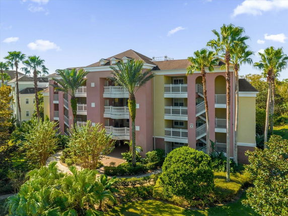 Front view of a multi-story building with balconies and palm trees.