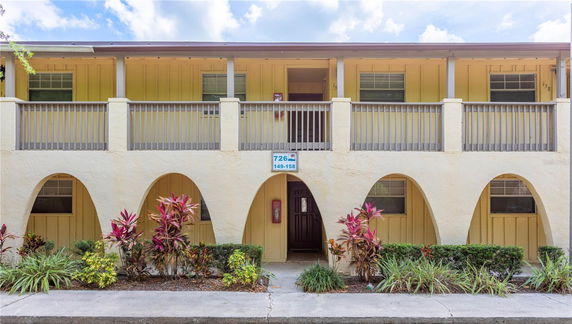 Front view of a two-story building with arched entryways and a balcony.