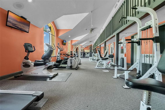 Interior view of a gym with various exercise equipment and bright orange walls.