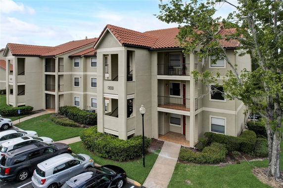 Front view of a three-story apartment building with balconies and a tiled roof.