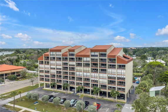 Front view of a multi-story building with red roof sections and numerous balconies.
