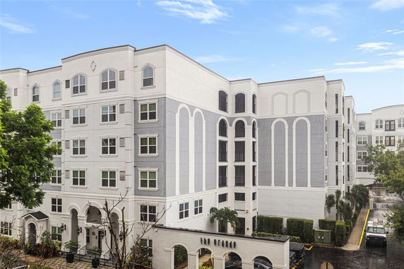 Front view of a multi-story residential building with decorative arches and multiple windows.