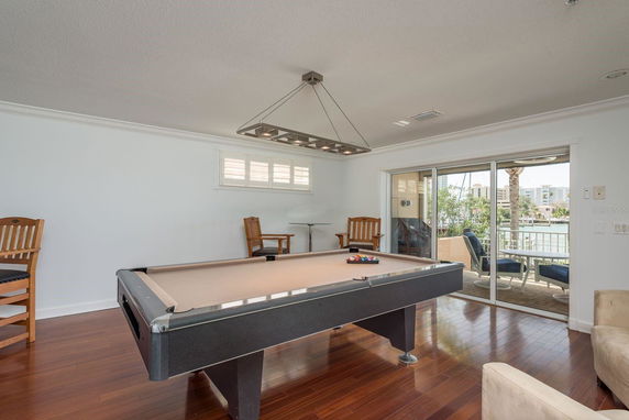 Room with a pool table and seating area, overlooking a balcony.