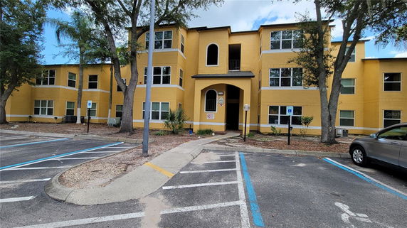 Front view of a yellow three-story apartment building with multiple windows.