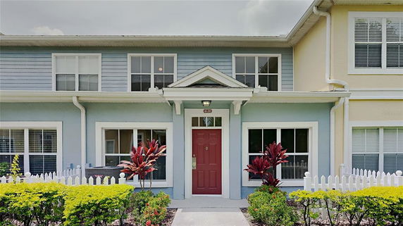 Front view of a two-story townhouse with a red door and blue siding.