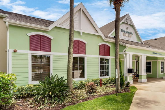 Front view of a light green building with red shutters and a gabled roof.
