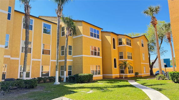 Front view of a multi-story yellow building with large windows.