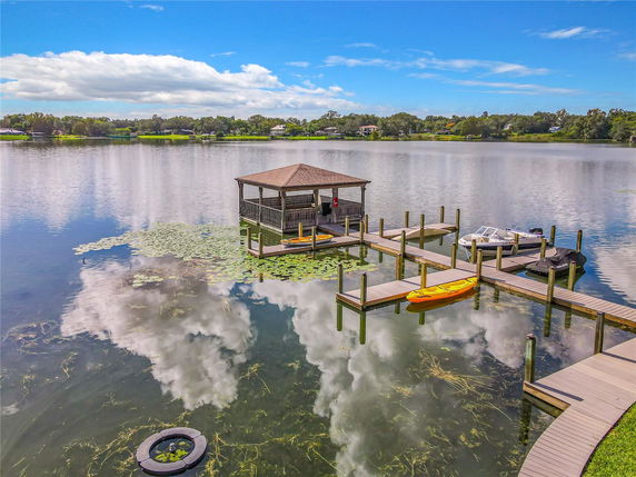 Scenic view of a lake with a dock, boats, and a gazebo over the water.