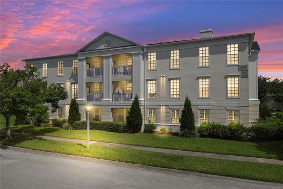 Front view of a three-story building with balconies and illuminated windows.