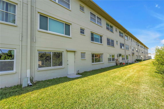 Side view of a multi-story residential building with multiple windows and doors on the ground level.