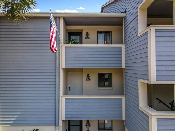 Front view of a multi-story apartment building with balconies and a flag.