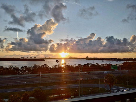 Panoramic view of a sunset over a body of water with buildings in the background.