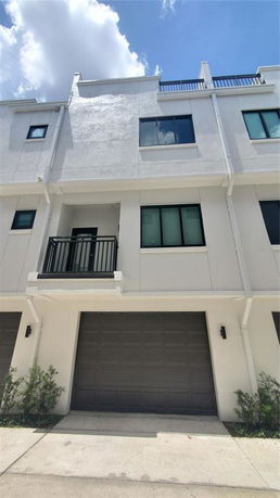 Front view of a multi-story building with a garage and balcony.