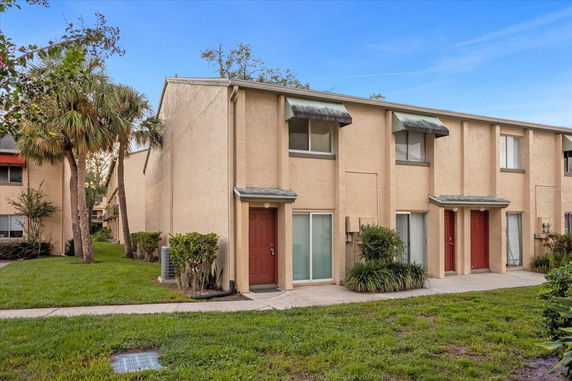 Front view of a two-story townhouse with multiple entrances and small awnings above windows.