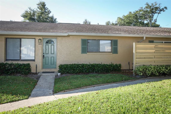 Front view of a single-story house with a green door and window shutters.