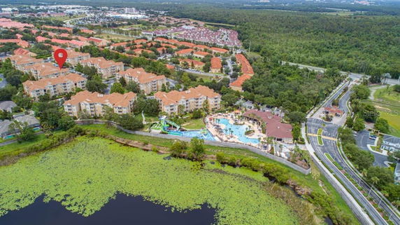 Aerial view of multiple residential buildings with orange roofs, a pool area, and surrounding greenery.