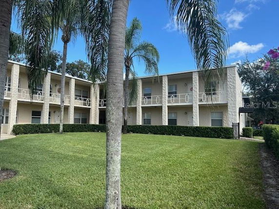 Front view of a two-story building with balconies and palm trees.