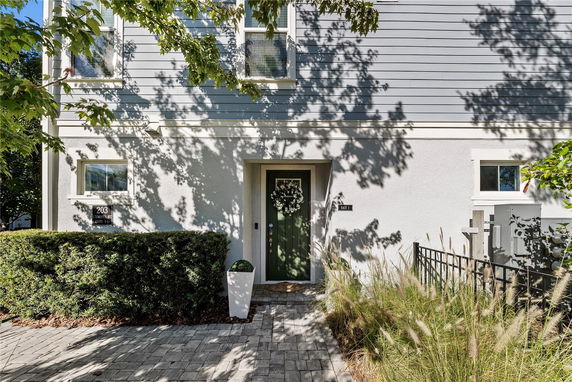 Front view of a house with a decorated entrance door and surrounding foliage.