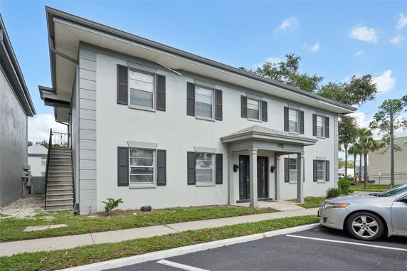 Front view of a two-story building with black shutters and a small portico entrance.