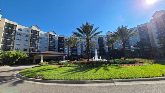 Front view of a multi-story apartment building with balconies and a landscaped entrance.