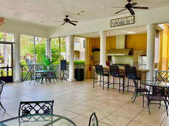 Indoor area with seating, ceiling fans, and a kitchen countertop with stools.