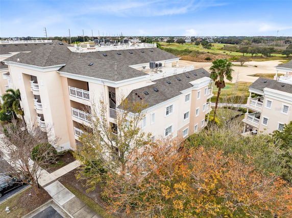 Panoramic view of a multi-story residential building with a rooftop and adjacent greenery.