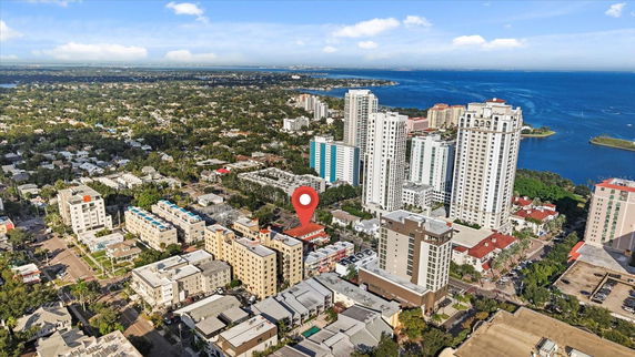 Aerial view of a cityscape with various buildings and a body of water in the background.