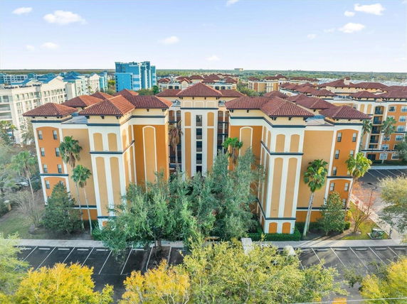 Front view of a large residential building with decorative columns and red-tiled roofs.