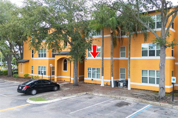 Front view of a yellow three-story apartment building with windows and a small entrance.