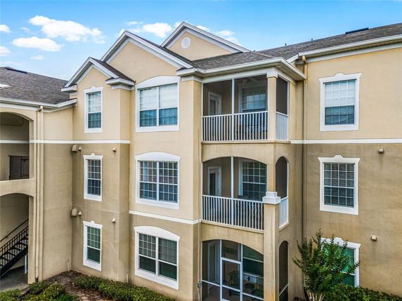 Front view of a multi-story residential building with balconies and arched windows.