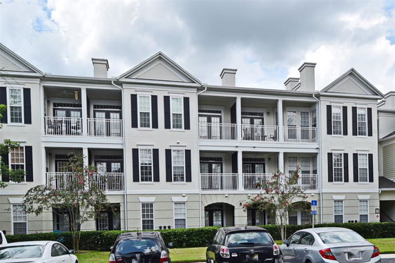 Front view of a multi-story apartment building with balconies and parked cars.