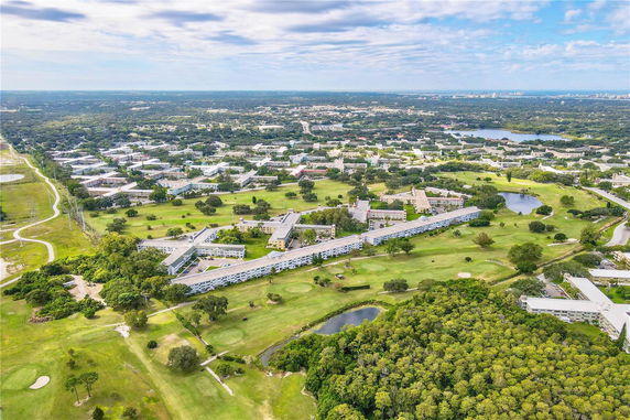 Aerial panoramic view of a residential complex with green spaces and surrounding landscape.