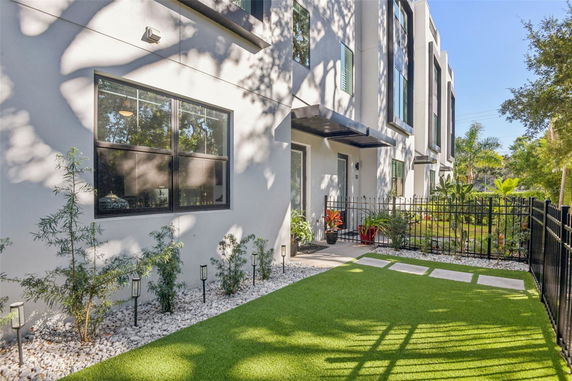 Front view of a modern multi-story building with large windows and a small landscaped area.