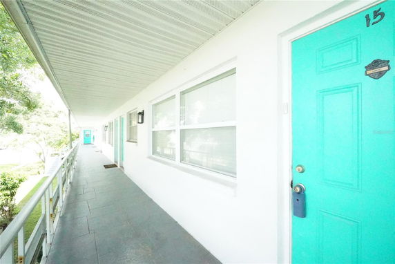 Front view of an apartment walkway with turquoise doors and windows.