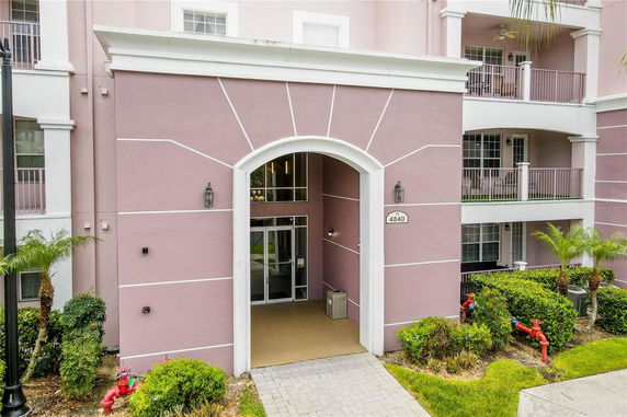 Front view of a multi-story building with a prominent arched entrance painted in pink and white.