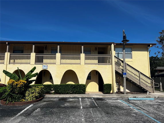 Front view of a two-story building with arched entryways and an external staircase.