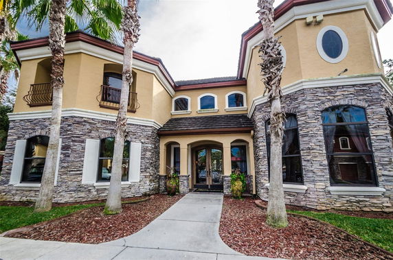 Front view of a two-story house with stone facade and multiple windows.