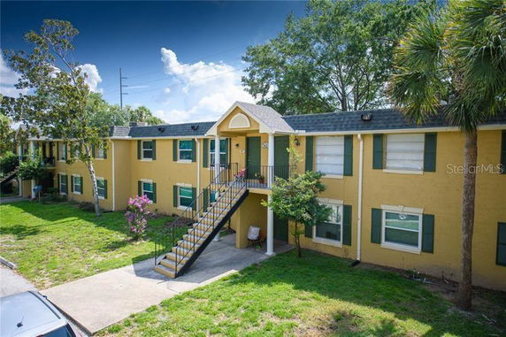 Front view of a two-story apartment building with external stairs and yellow exterior.